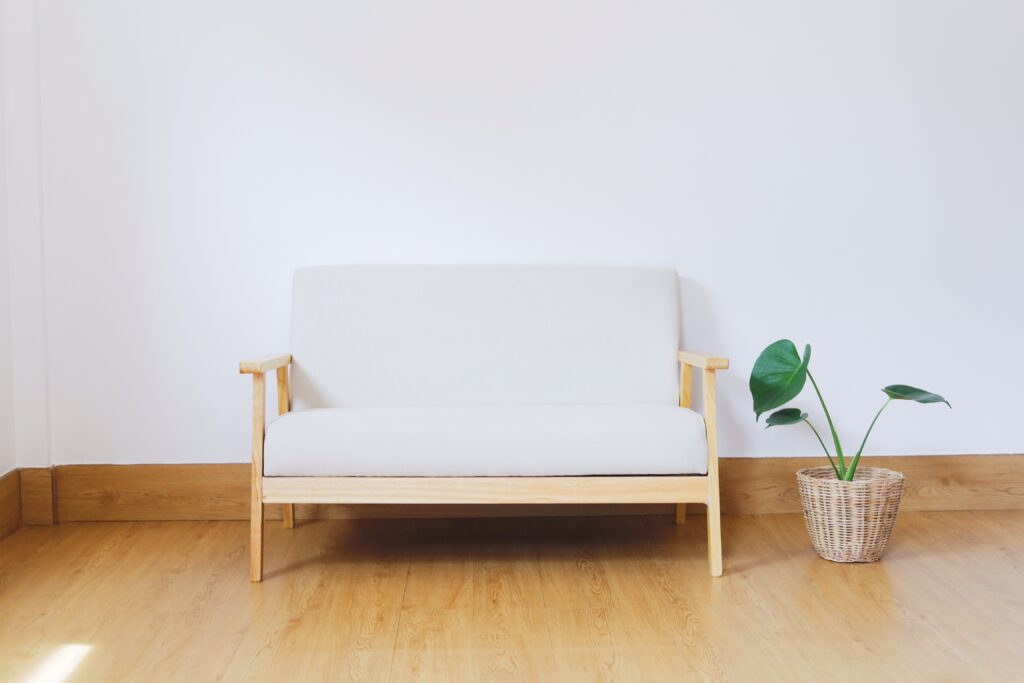 Zimmer mit einer Bank und einer Pflanze, weiße Wand, heller Boden, minimalistisch eingerichtet